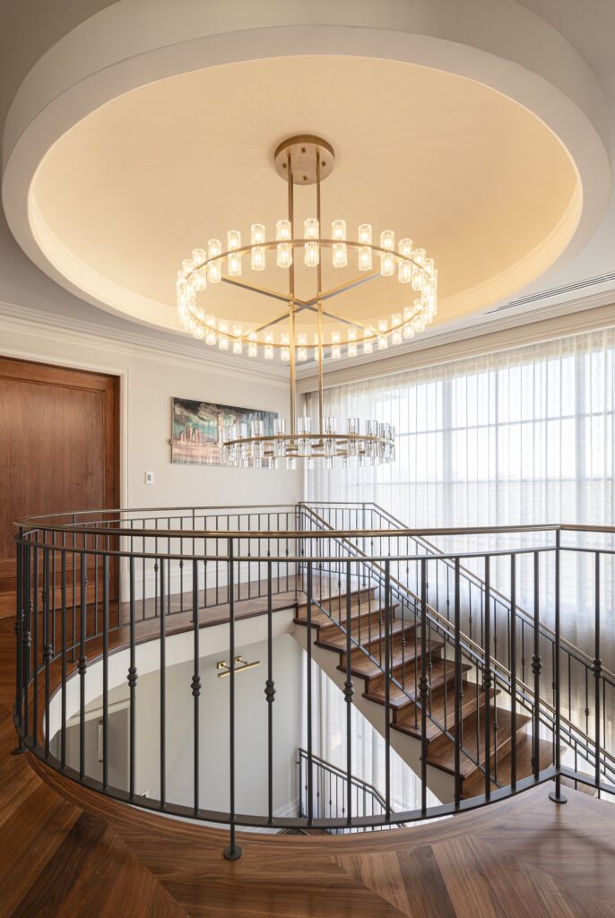 Upper staircase landing beneath a circular chandelier