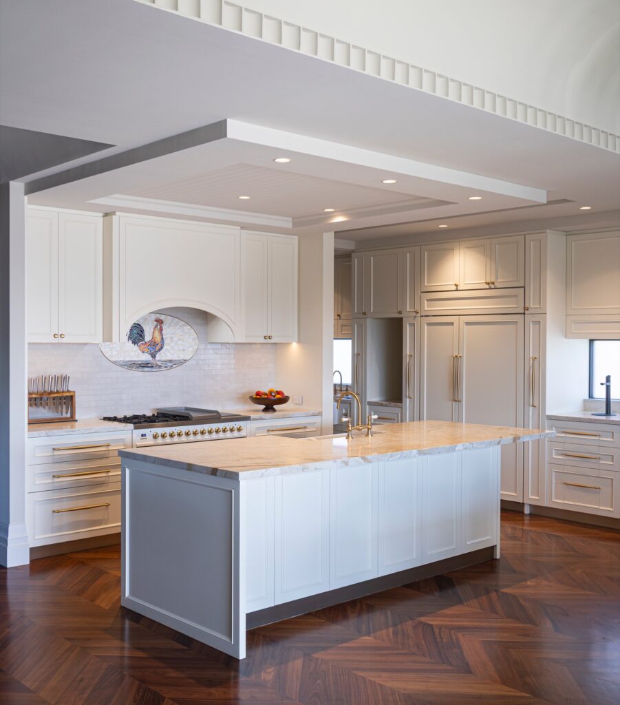 Light-filled kitchen with a stone island, herringbone timber floor and brass details